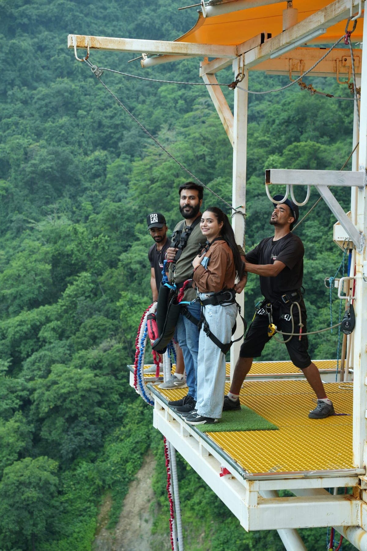 A couple harnessed on the 111 m bungee platform above the valley near Laxman Jhula, Rishikesh