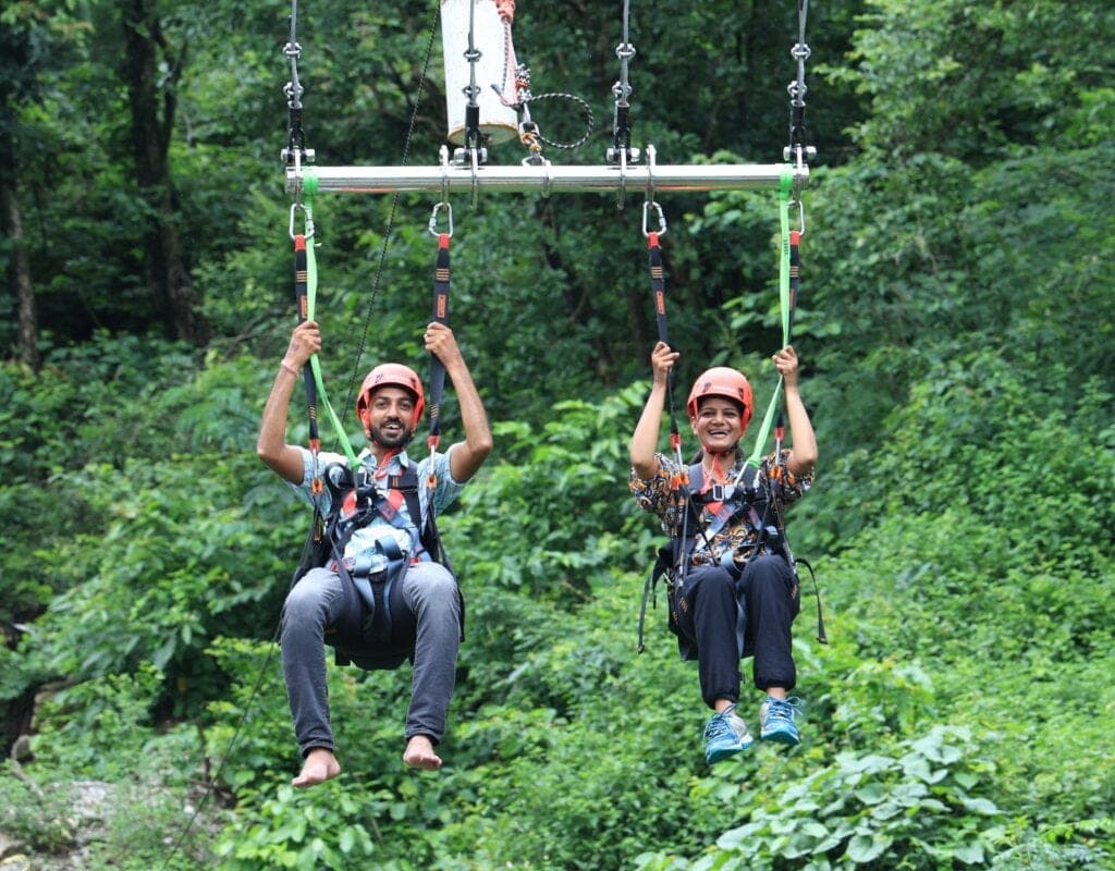 A couple mid-swing on the giant swing over the forested valley near Laxman Jhula, Rishikesh