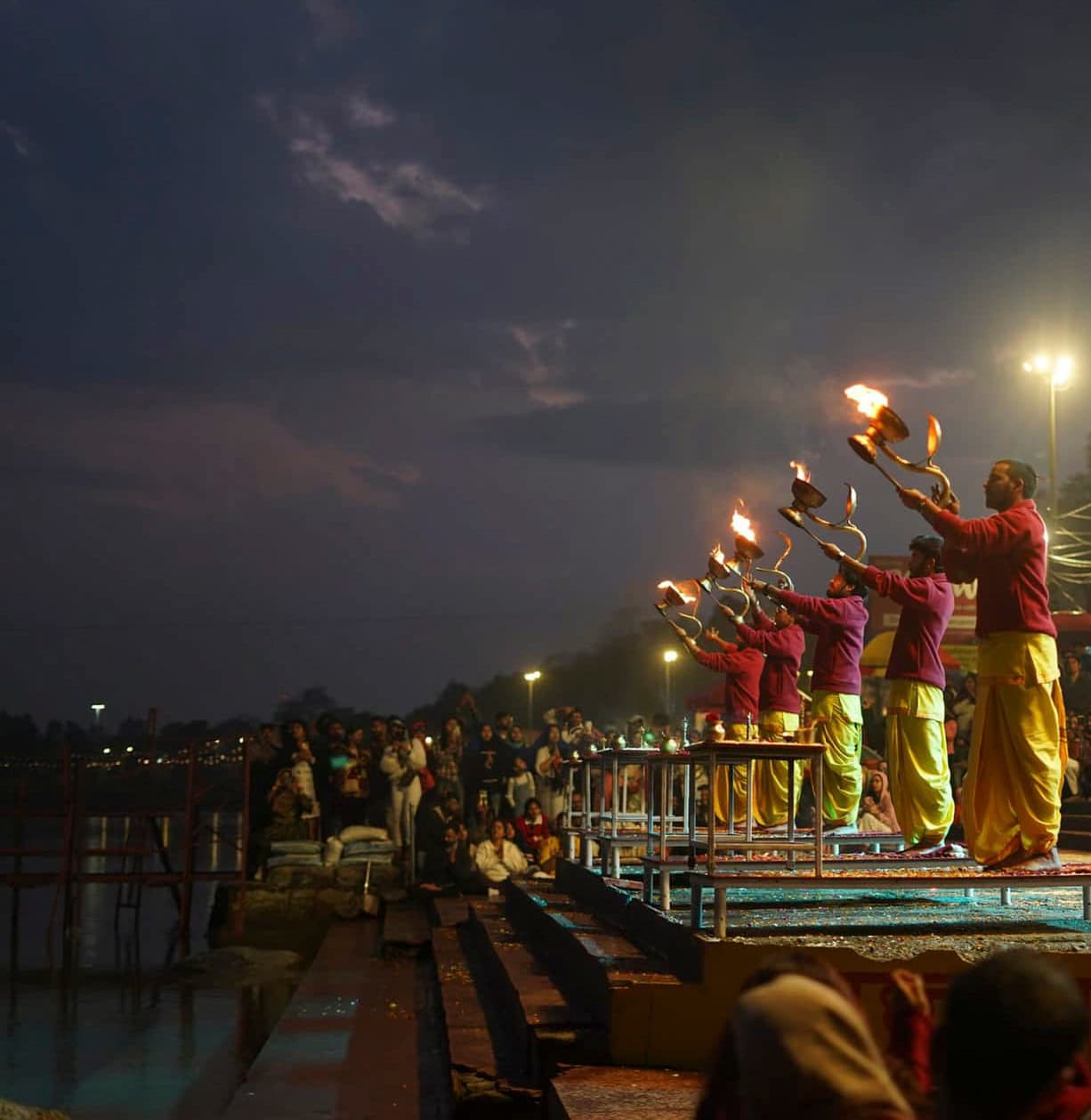 Rows of fire lamps raised over the Ganga at dusk during the evening aarti in Rishikesh