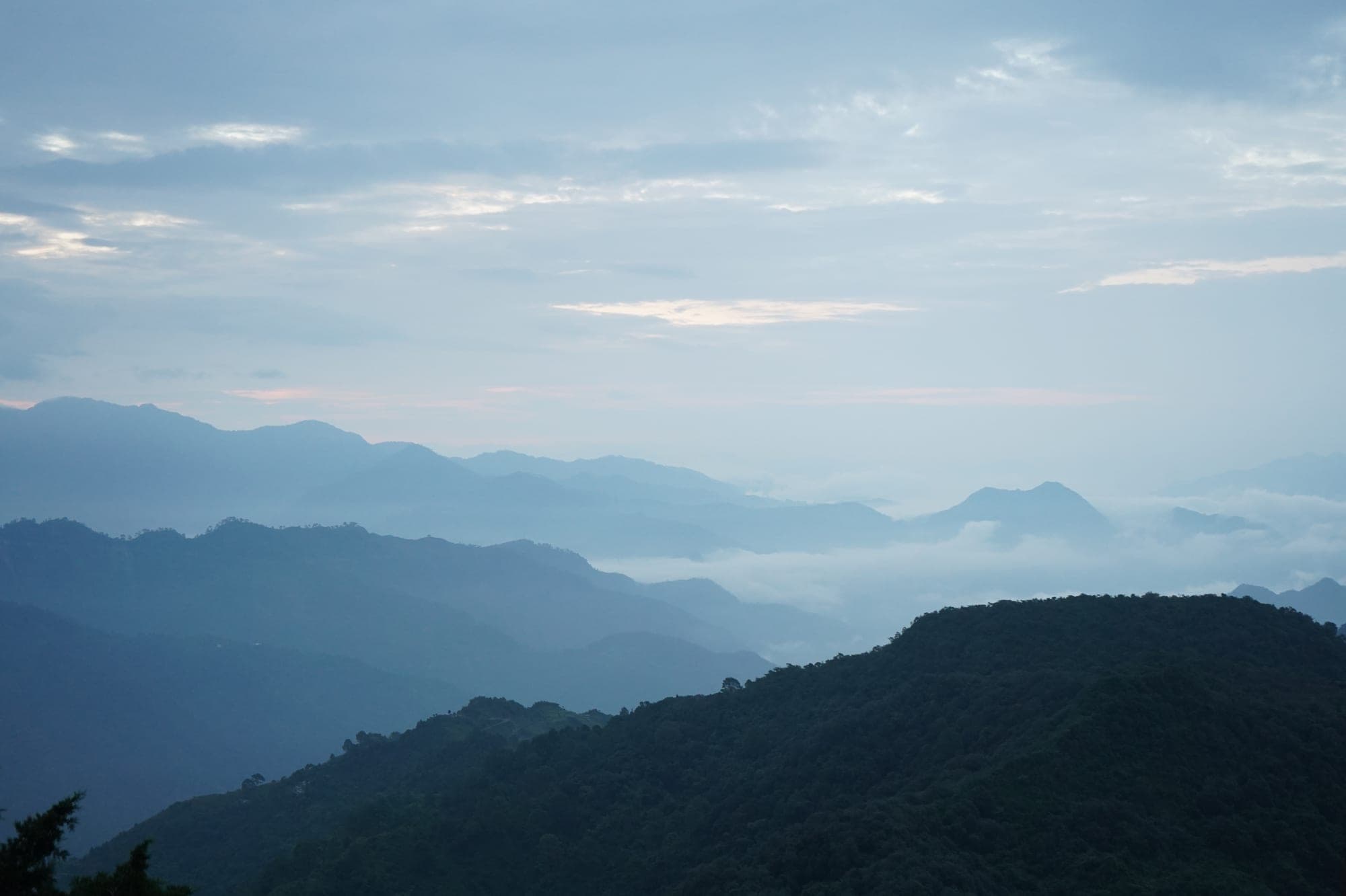 Layered forested Himalayan foothill ridges receding into haze above the valley near Rishikesh