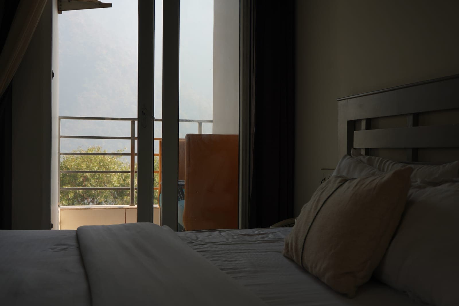 The bed with balcony door, Deluxe Room with Balcony at Aroma Cafe Hotel, Rishikesh