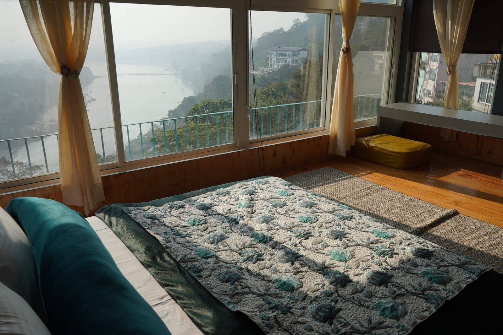 The Loft room's bed, with the Ganga view through the window, at Aroma Cafe Hotel, Rishikesh