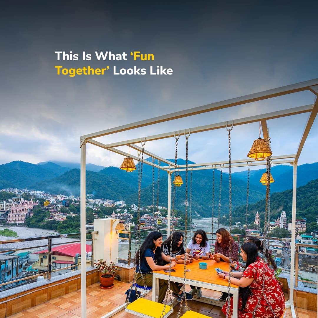 Rooftop seating with a daytime view of Rishikesh and the Lakshman Jhula bridge at goSTOPS Rishikesh, Lakshman Jhula