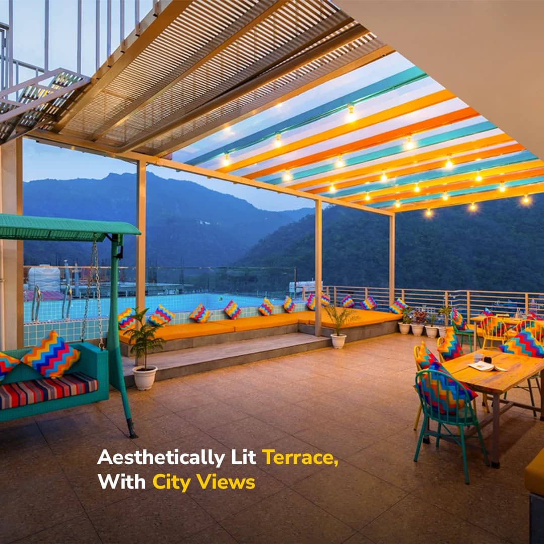 Rooftop terrace lounge seating by the pool, lit up in the evening, at goSTOPS Rishikesh, Tapovan PLUS