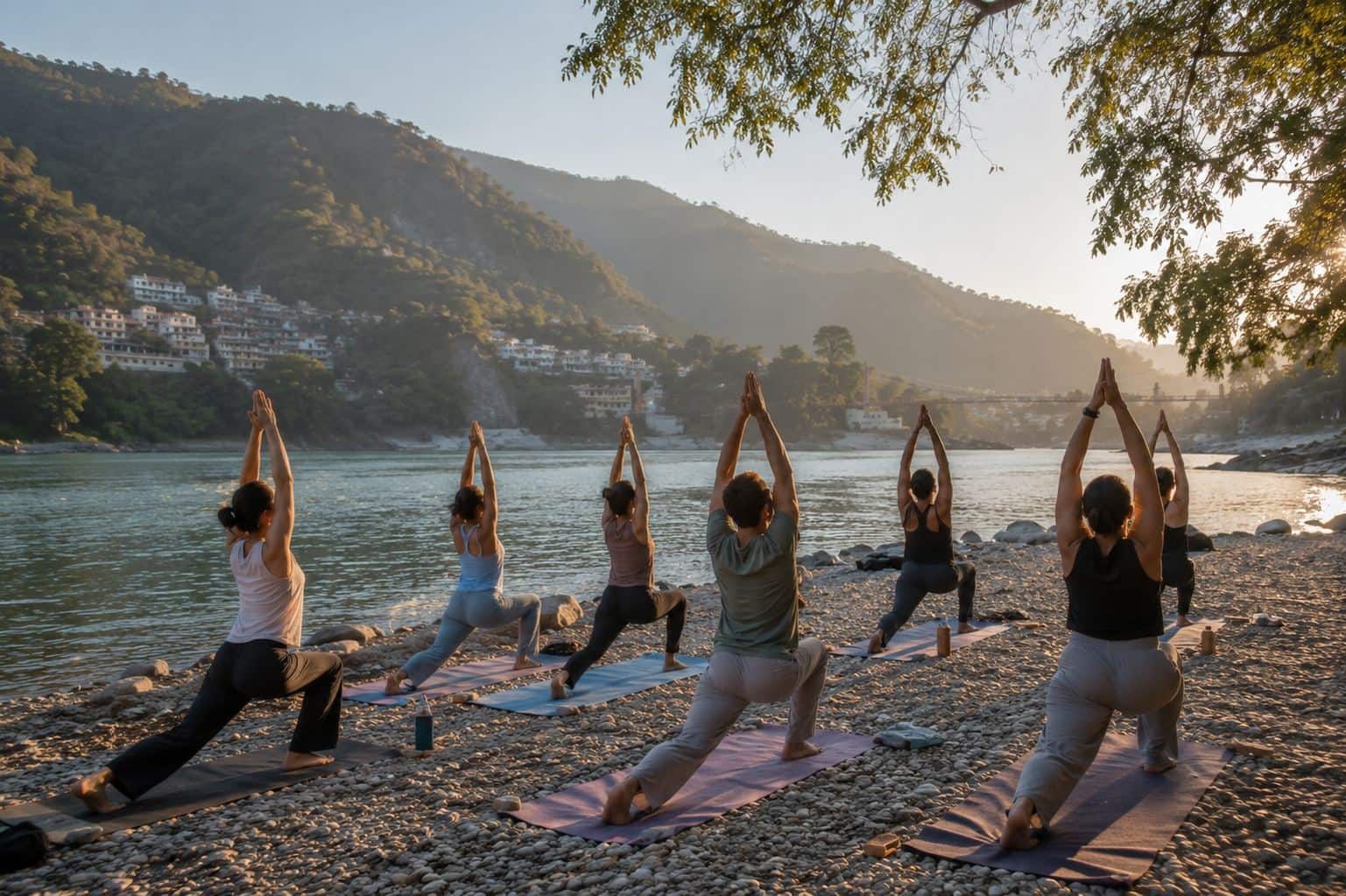A sunrise yoga class on the Ganga riverbank in Rishikesh, a row of practitioners holding warrior pose on their mats
