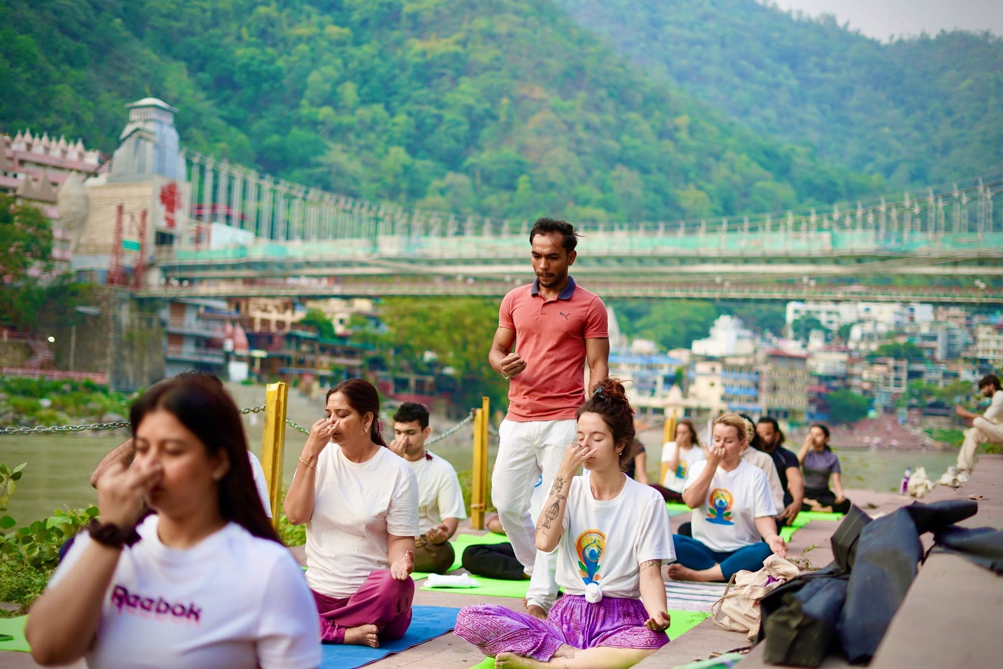 A breathwork session on the riverbank below Laxman Jhula in Rishikesh, practitioners seated facing the Ganga