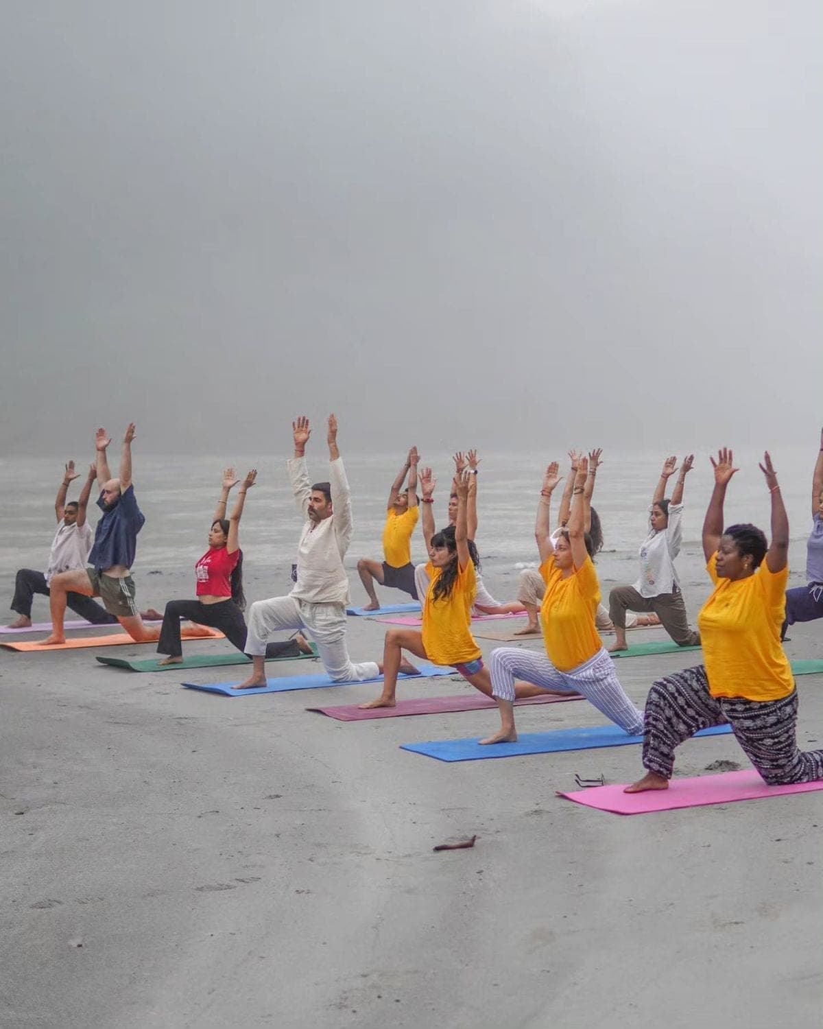 A group practising yoga together on the misty riverbank in Rishikesh