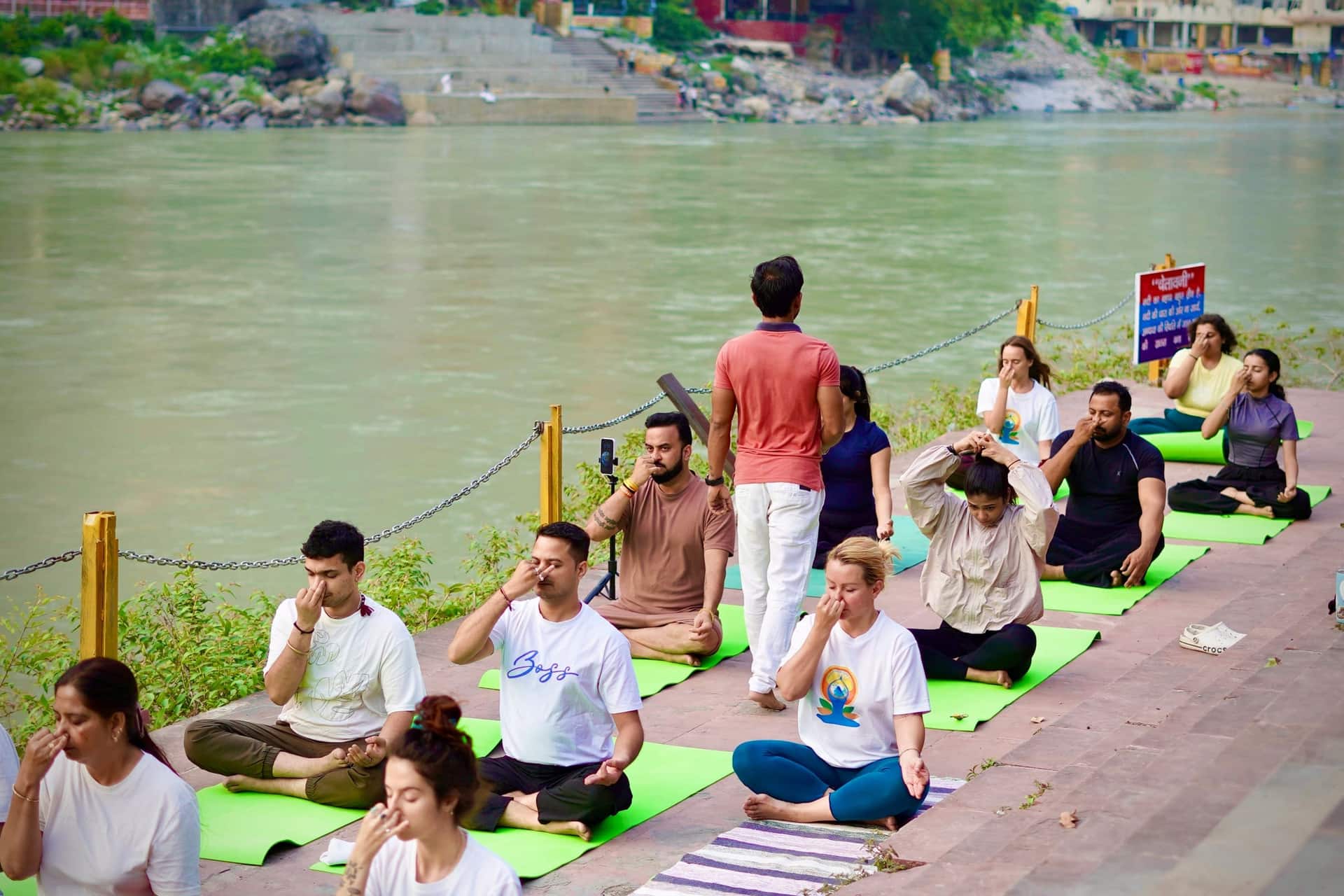 A group seated for pranayama practice beside the Ganga in Rishikesh