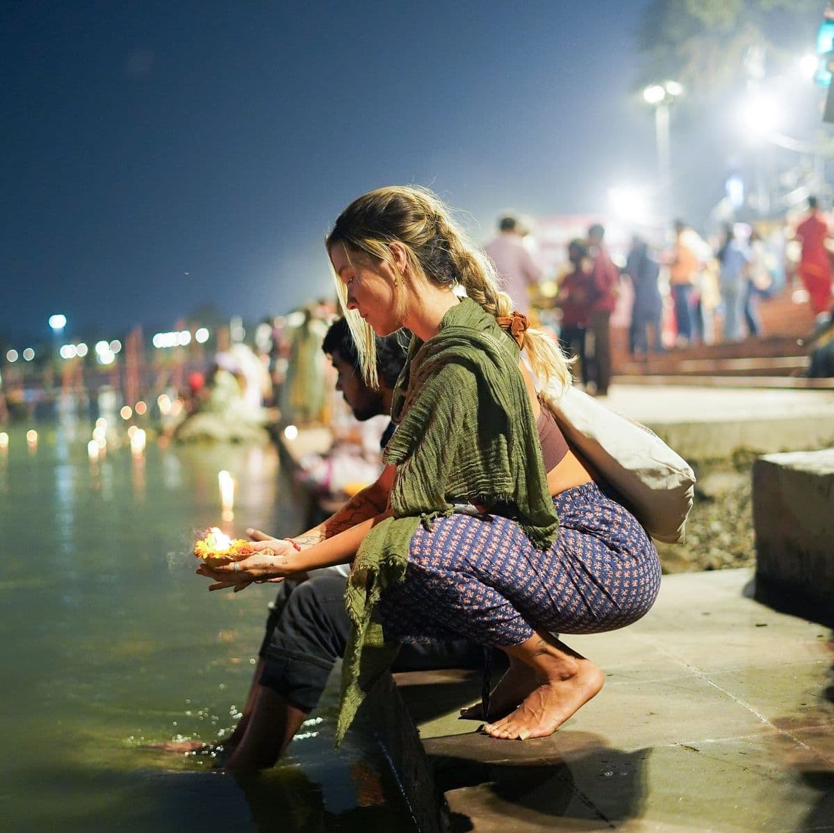 A guest offering a flower diya to the Ganga after evening aarti